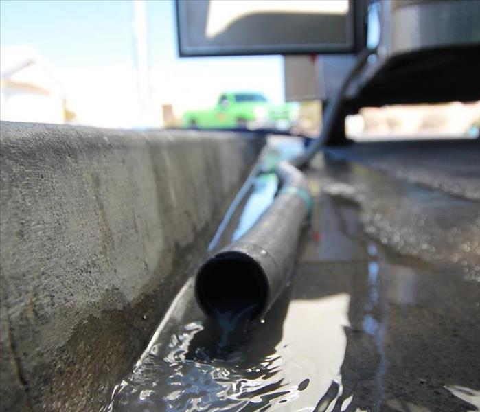 A hose with water coming out from our water extractor after restoring a flooded home.