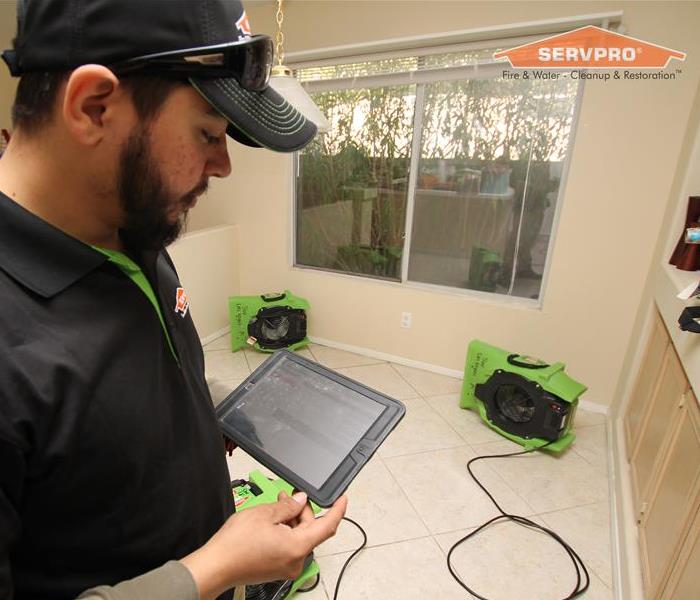 Our technician assessing the damages from a storm in a home while fans are drying the floors.